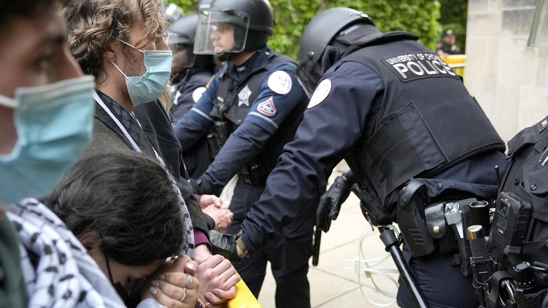 A pro-Palestinian protester rests her head on her clasped hands while she stands before University of Chicago police officers while officers kept protesters from the university's quad while the student encampment is dismantled Tuesday, May 7, 2024, in Chicago. (AP Photo / Charles Rex Arbogast)