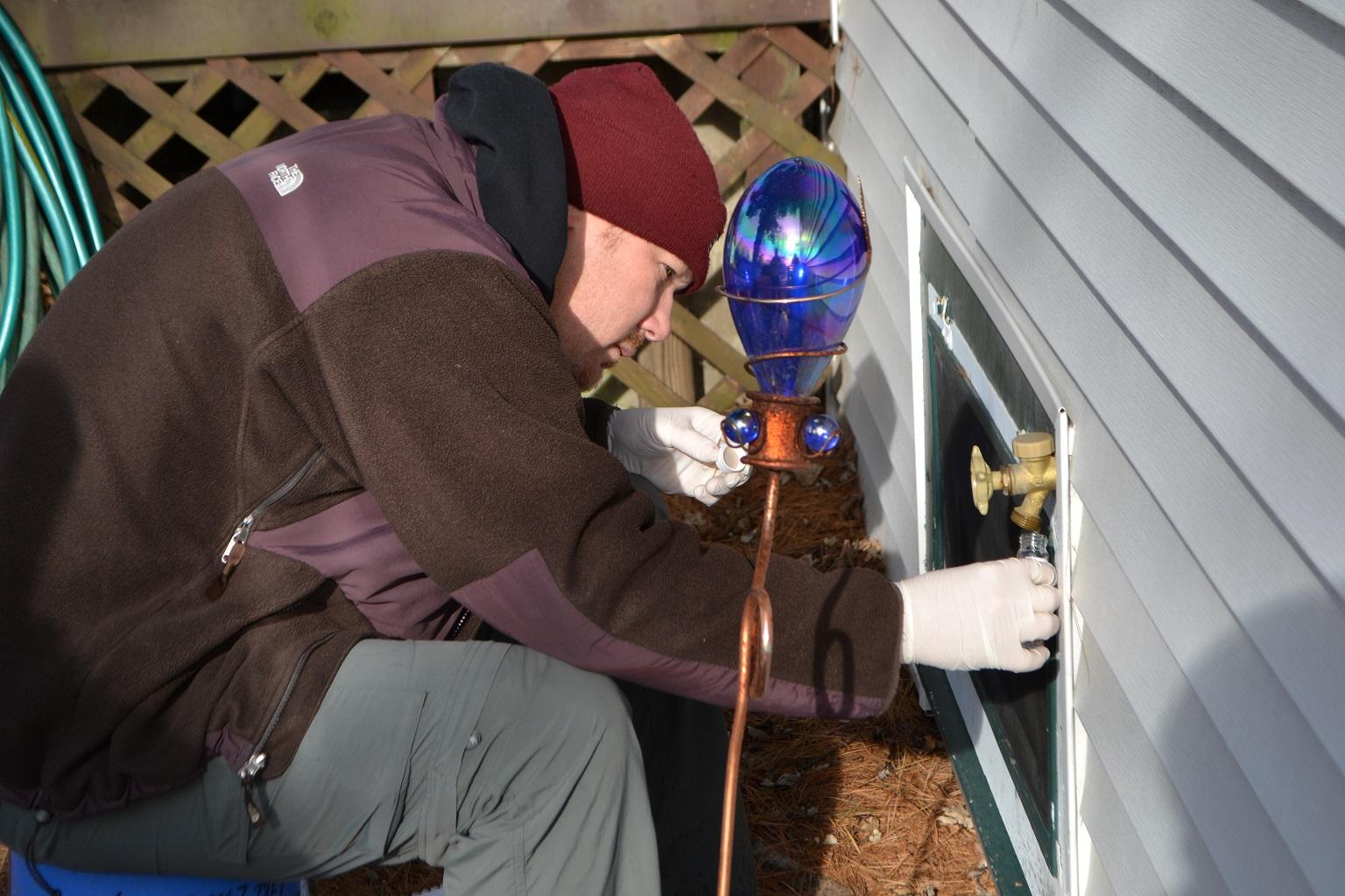 Ryan Bennett, an environmental protection geologist with the Illinois EPA, collects water samples from a home in Willowbrook on Thursday. (Alex Ruppenthal / WTTW) 