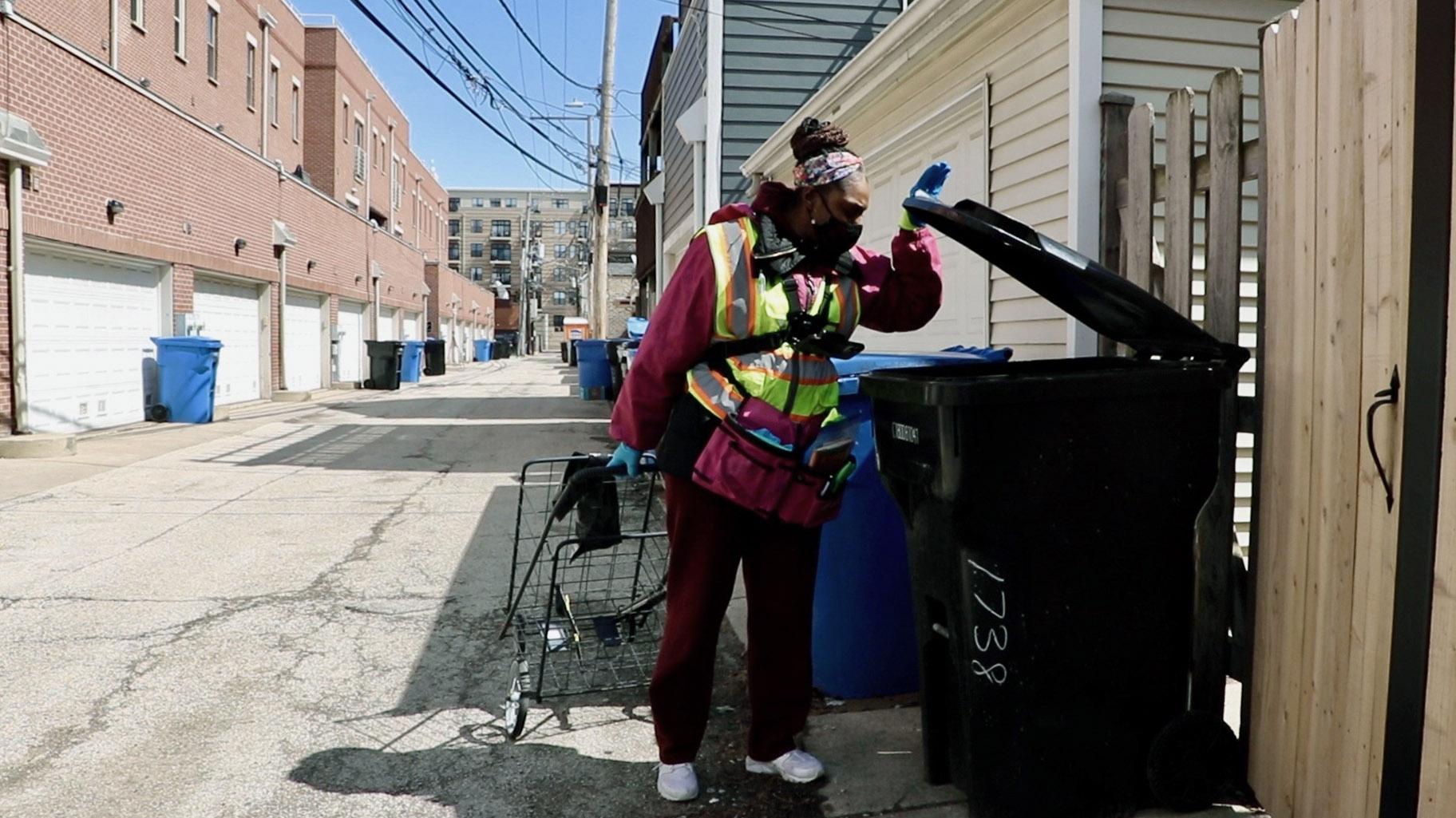 Angel Williams looks through a garbage can in Chicago’s Roscoe Village neighborhood on April 1, 2022. In 2021, Williams wrote and published a book on her entrepreneurial journey as a dumpster diver. (Evan Garcia / WTTW News)