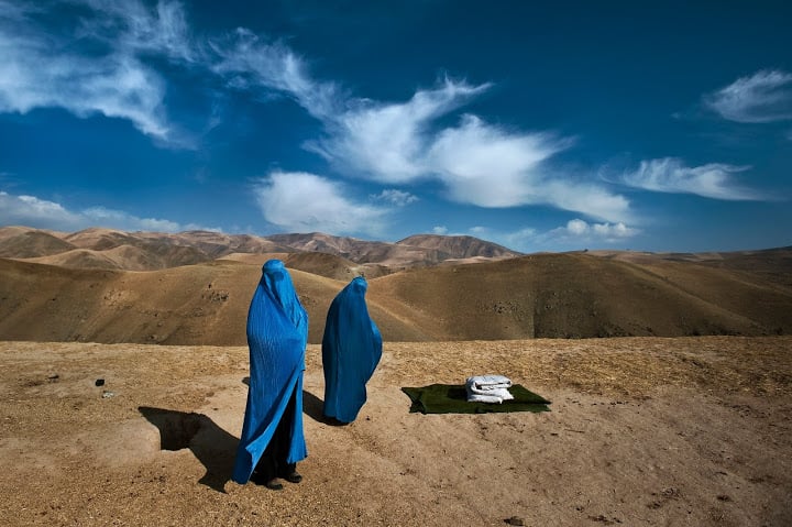 Two women from Weha Village in Afghanistan wait on the side of the road for transportation to the hospital after their vehicle had broken down during the four-hour commute. One of the women is pregnant with her first child and her water has just broke. (Lynsey Addario)