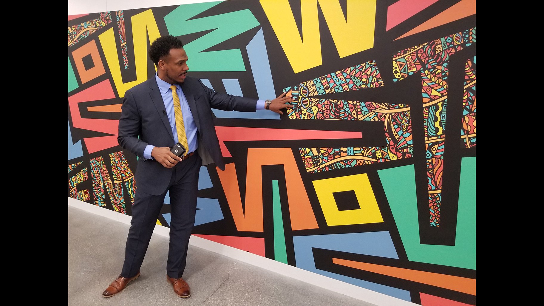 Englewood STEM Principal Conrad Timbers-Ausar shows off one of the murals inside his school's building. (Matt Masterson / WTTW News)