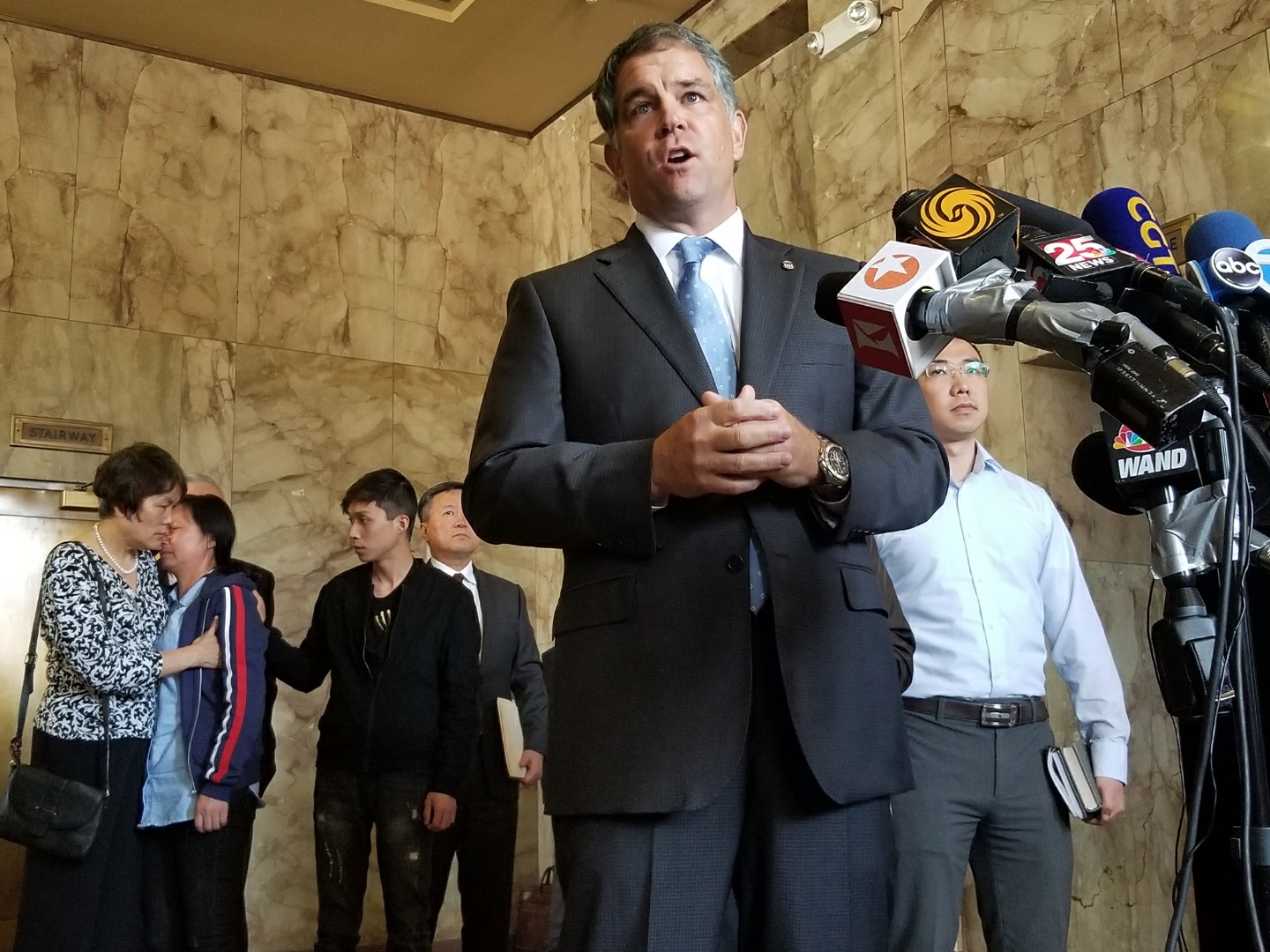 John Milhiser, U.S. attorney for the Central District of Illinois, speaks to the press in Peoria’s federal courthouse following the sentencing of Brendt Christensen on July 18, 2019 while Yingying Zhang’s mother cries in the background. (Matt Masterson / WTTW News)