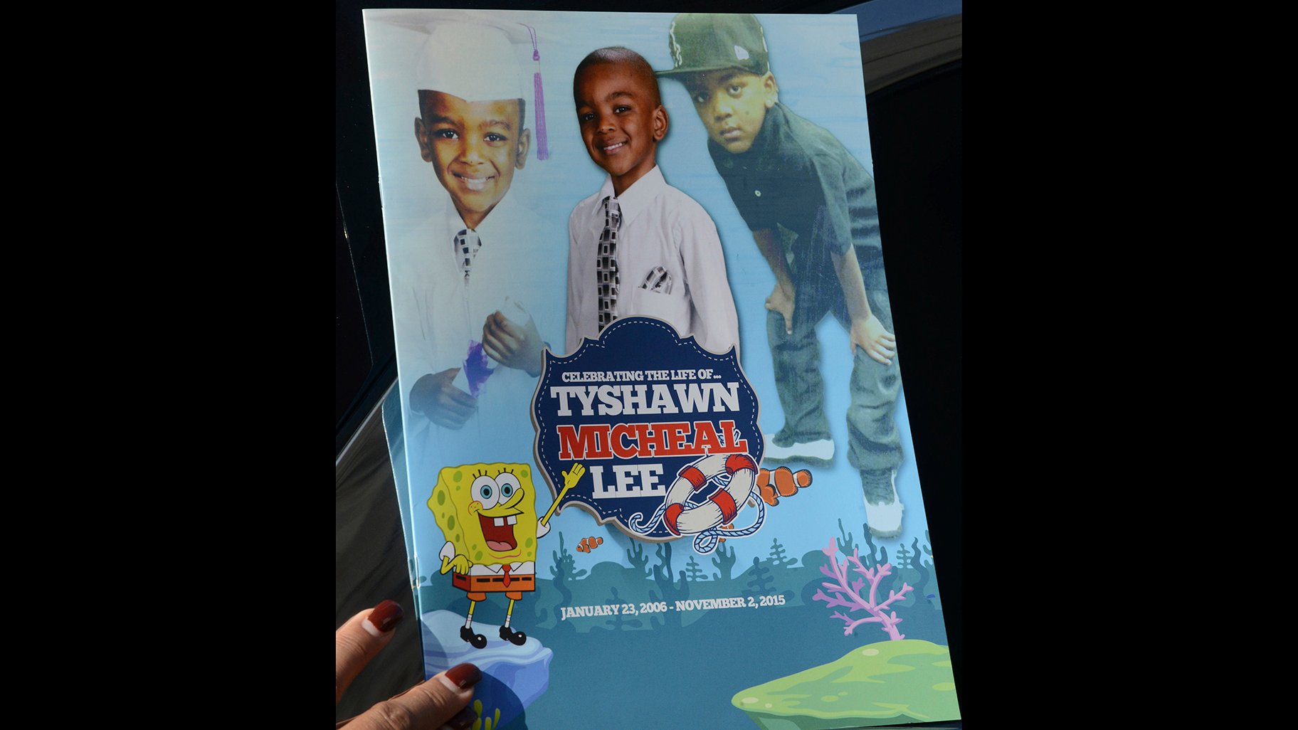 In this Tuesday, Nov. 10, 2015, file photo, a mourner holds the program for the funeral of 9-year-old Tyshawn Lee at St. Sabina Church in Chicago. (Brian Jackson / Chicago Sun-Times via AP, File)