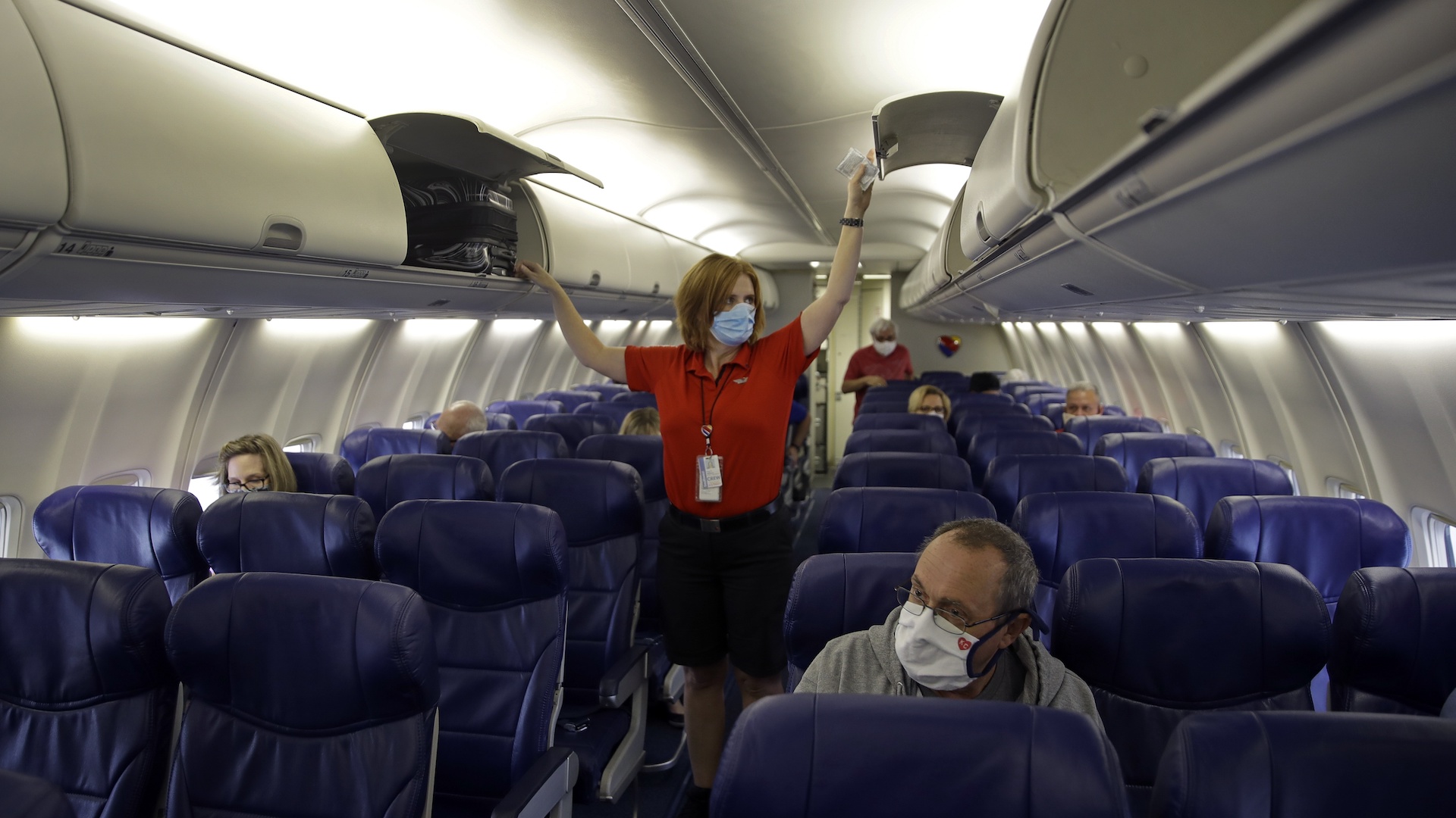 In this May 24, 2020, file photo, a Southwest Airlines flight attendant prepares a plane bound for Orlando, Fla. for takeoff at Kansas City International airport in Kansas City, Mo. About 40,000 workers in the airline industry are facing layoffs on Thursday, Oct. 1, unless Congress comes up with another aid package. (AP Photo/Charlie Riedel, File)
