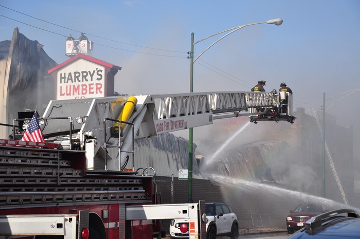 A rainbow appears through dark clouds of smoke as firefighters work to extinguish a 3-alarm fire at Harry’s Lumber Company (Sean Keenehan)