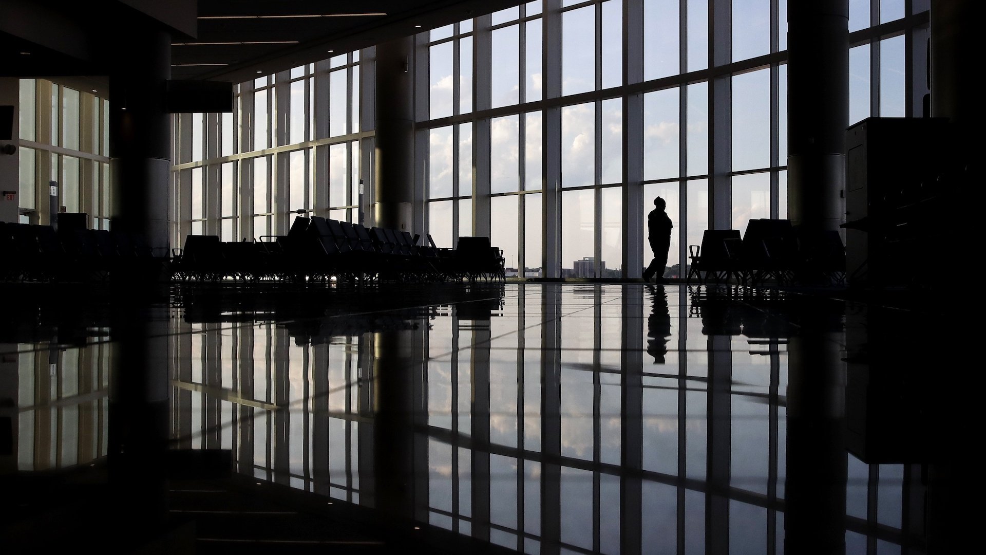 In this June 1, 2020 file photo, a woman looks through a window at a near-empty terminal at an airport in Atlanta. The coronavirus pandemic has taken a harsh toll on the mental health of young Americans, according to a new poll. (AP Photo/Charlie Riedel, File)