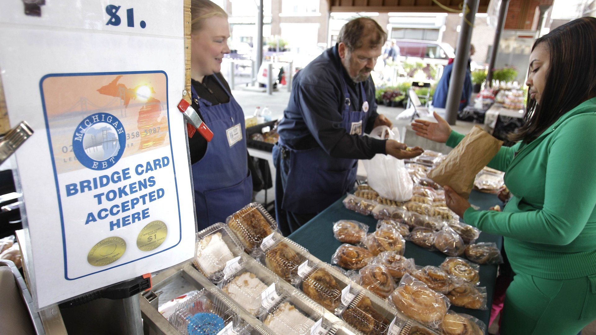 In a Sept. 11, 2010, file photo, Temeka Williams, right, of Detroit, uses her bridge card tokens for a purchase from Elizabeth and Gary Lauber from Sweet Delights at the Farmer's Market in Detroit. Farmers, growers and operators of open-air markets are heading into a busy time of the year, in early May 2020, as many states still are under stay-at-home orders for residents and non-essential businesses to slow the spread of the new coronavirus. (AP Photo/Carlos Osorio, File)
