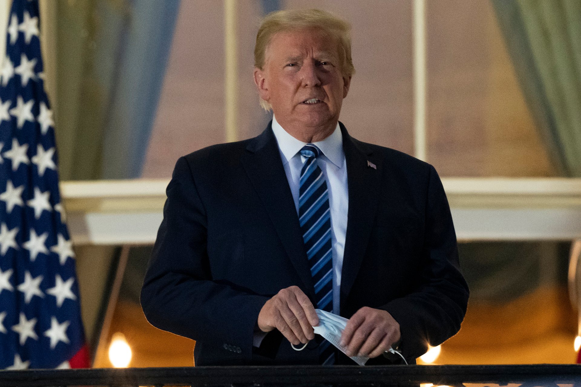  In this Monday, Oct. 5, 2020 file photo, President Donald Trump holds his mask after removing it from his face as he stands on the Blue Room Balcony upon returning to the White House in Washington from the Walter Reed National Military Medical Center in Bethesda, Md. He announced he tested positive for the coronavirus on Oct. 2. (AP Photo/Alex Brandon)