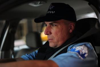 A stunt driver, dressed as a Chicago police officer, readies for the scene to start.