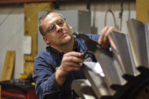 An Excel worker uses calipers to measure a component of a cone crusher, used in open-pit mining. / Michael Lipkin