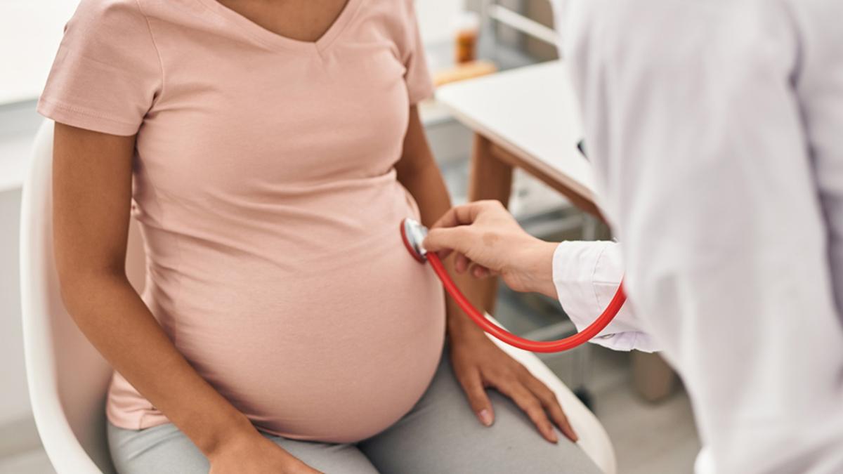 A doctor listens to a pregnant woman’s abdomen using a stethoscope. (Krakenimages.com / Adobe Stock)