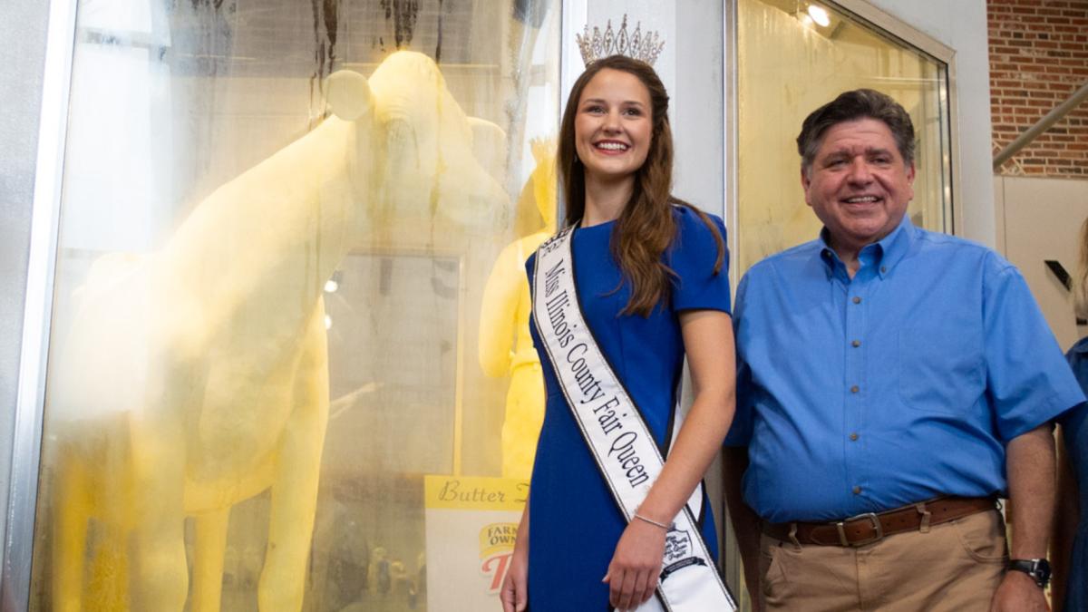 Illinois State Fair Queen Krista Phillips and Gov. JB Pritzker pose with the 2026 Illinois State Fair butter cow. (Jerry Nowicki / Capitol News Illinois)