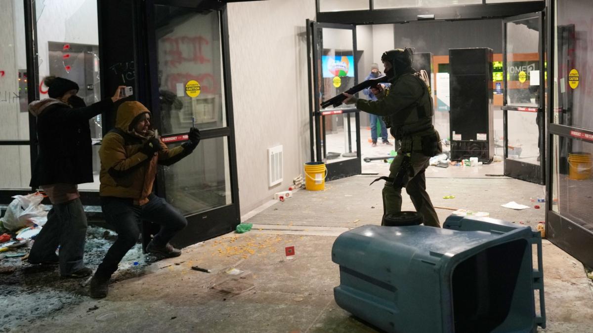 A federal agent points a weapon at a person outside a hotel during a noise demonstration protest in response to federal immigration enforcement operations in the city Sunday, Jan. 25, 2026, in Minneapolis. (AP Photo / Adam Gray)