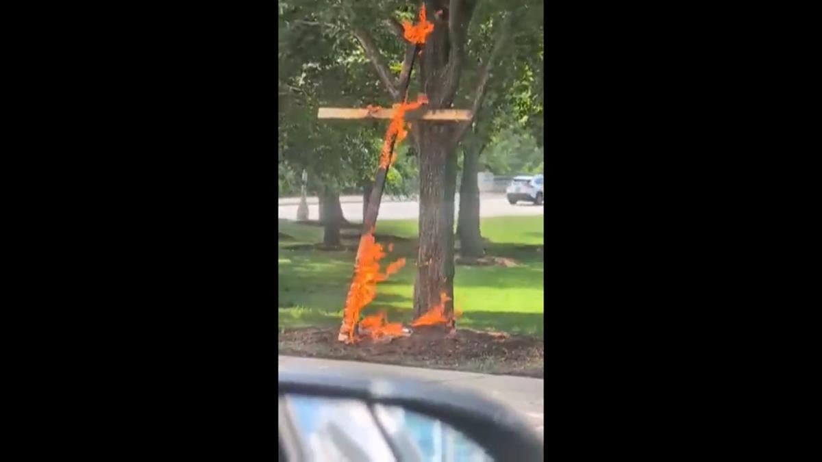 This grab from a video taken by motorist Keinika Carlton shows a wooden cross engulfed in bright orange flames as it leans against a tree in Grant Park, Chicago, Illinois, on Tuesday, July 9, 2026. (Keinika Carlton via AP)