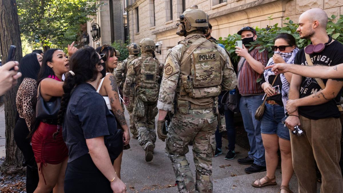 Pedestrians yell at federal agents from U.S. Immigration and Customs Enforcement and U.S. Customs and Border Protection as they walk along North Clark Street near West Oak Street in the River North neighborhood, Sunday, Sept. 28, 2025, in Chicago. (Ashlee Rezin/Chicago Sun-Times via AP)