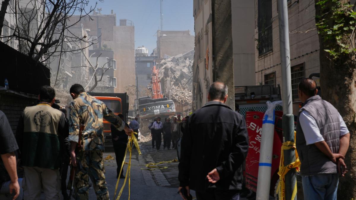Bystanders watch from a distance as rescue teams and first responders work at the site of a strike that, according to a security official at the scene, destroyed half of the Khorasaniha Synagogue and nearby residential buildings in Tehran, Iran, Tuesday, April 7, 2026. (AP Photo / Francisco Seco)
