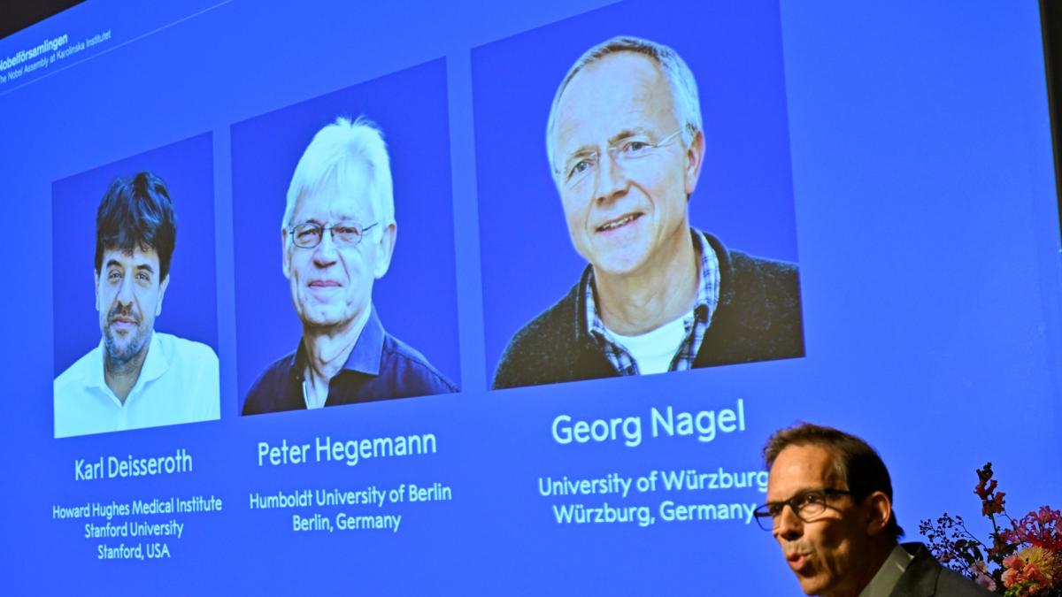 Karl Deisseroth, Peter Hegemann and Georg Nagel are shown on the screen as they are awarded the 2026 Nobel Prize in Physiology or Medicine, as announced during a press conference at the Nobel Forum at Karolinska Institutet in Stockholm, Sweden, Oct. 5, 2026. (Pontus Lundahl / TT News Agency via AP)