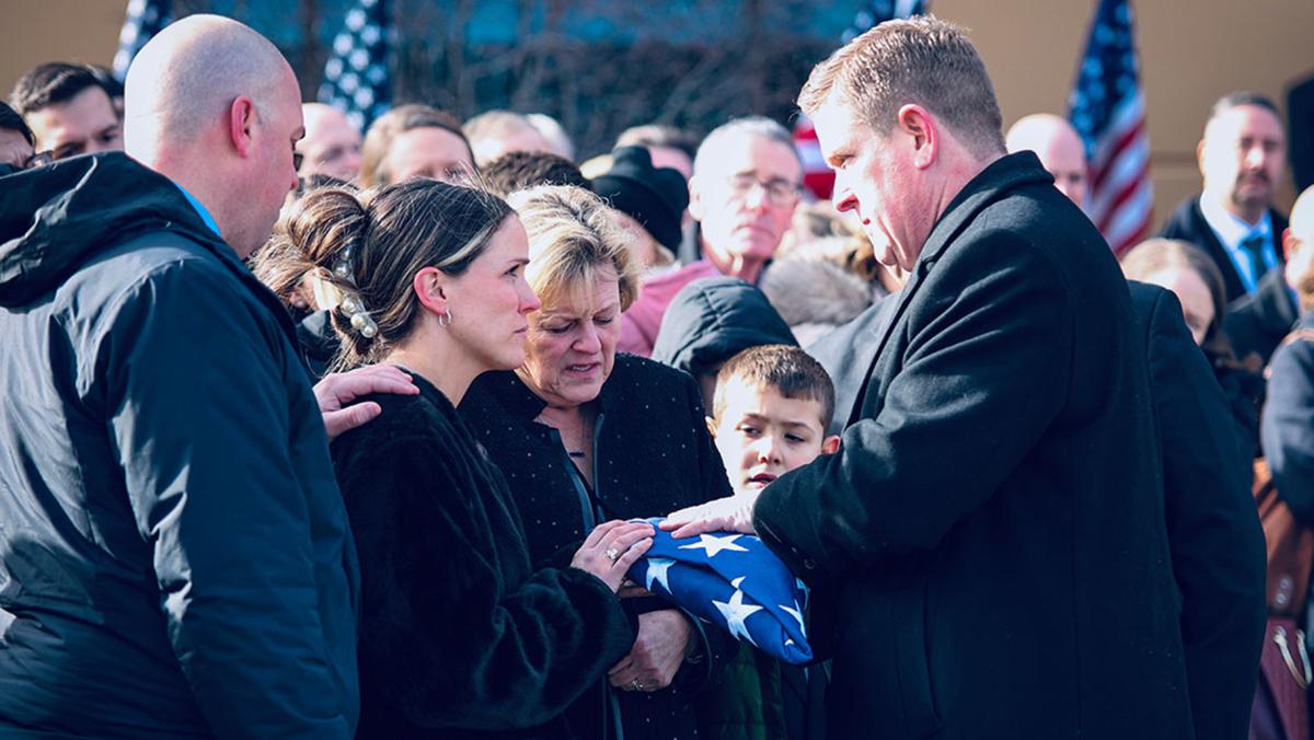 Illinois State Police Director Brendan Kelly hands a flag to Meghan Carns, the widow of Trooper Clay Carns, who died on Dec. 23, 2024. John Fleet, 69, of Wilmington, was charged with violating Scott’s Law, which is a Class 4 Felony. (Photo provided)
