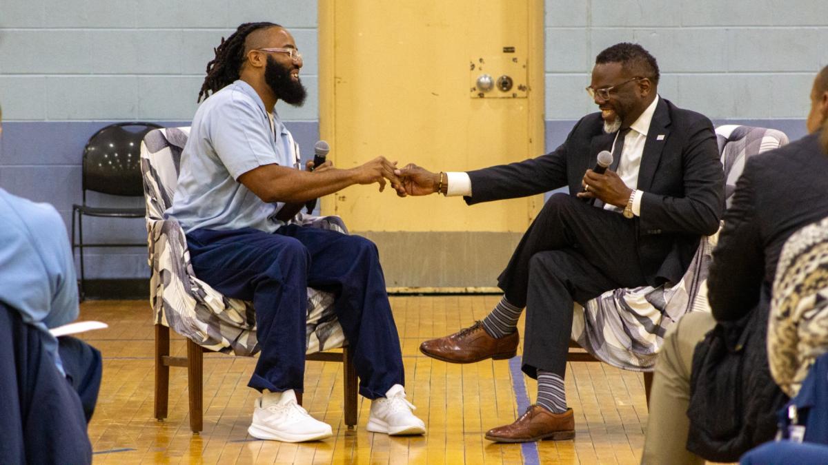 Incarcerated Northwestern University student André Patterson shakes hands with Chicago Mayor Brandon Johnson during his visit to Sheridan Correctional Center on Sunday, March 15, 2026. (Blair Paddock / WTTW News)