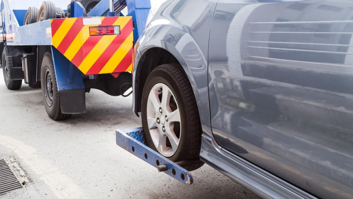 A car is towed by a tow truck. (Tam KC / iStock)