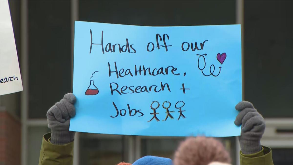 University of Illinois Chicago faculty hold signs denouncing possible federal funding cuts during a rally at the school on Feb. 19, 2025. (WTTW News)