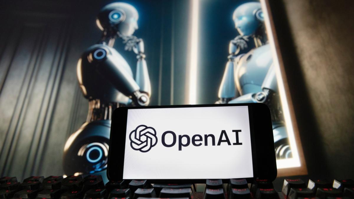 The OpenAI logo is displayed on a cellphone with an image on a computer monitor generated by ChatGPT's Dall-E text-to-image model, Dec. 8, 2023, in Boston. (AP Photo / Michael Dwyer, File)