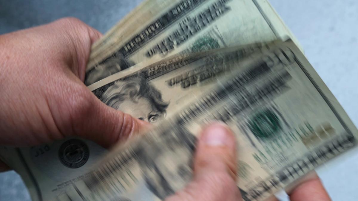 Hands holding a stack of money. (Elise Amendola / AP / File via CNN Newsource)