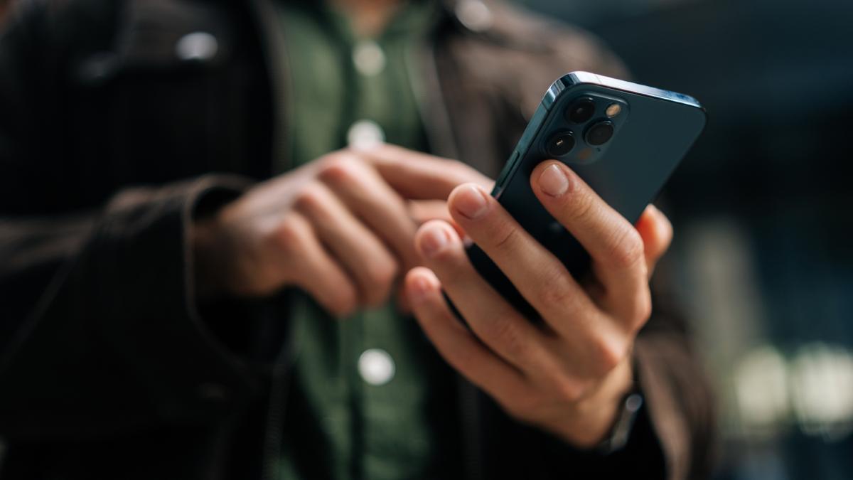A man types on a cell phone. A man types on a cell phone.