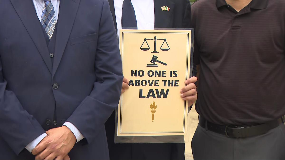 An attendee holds a sign during a press conference outside the Chicago Police Department’s 19th District Station on Aug. 10, 2026. (WTTW News)
