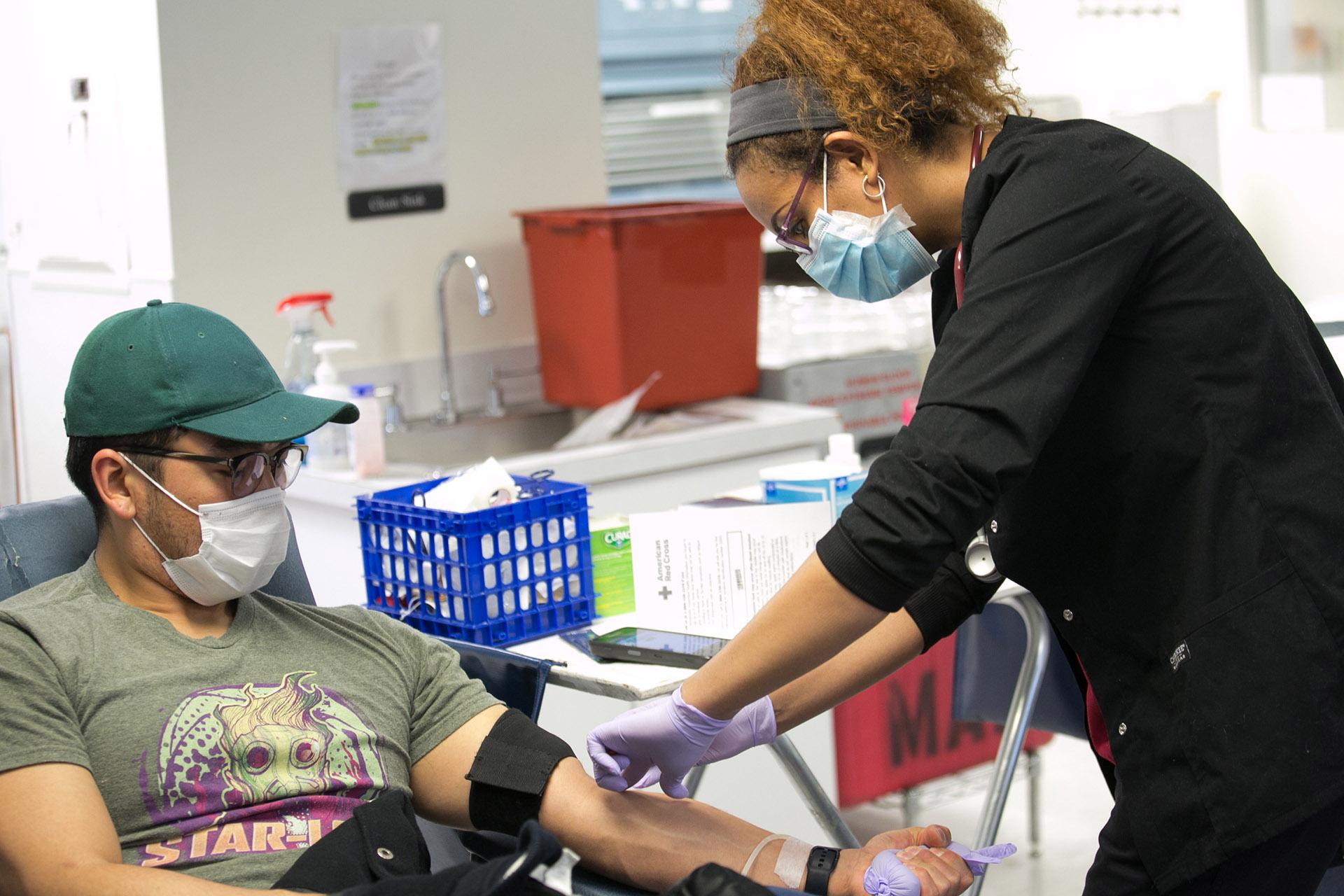 A Red Cross blood donor rolls up a sleeve to give blood during the COVID-19 outbreak at the Rockville Donation Center in Maryland. (Photo by Dennis Drenner / American Red Cross)