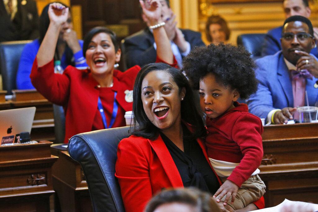 In this Jan 27, 2020, file photo, Virginia Delegate Jennifer Carroll Foy holds her son, Alex Foy, as she and Delegate Hala Ayala, D-Prince William, back, celebrate the passage of the Equal Rights Amendment in the House chambers at the Capitol in Richmond, Va. (AP Photo / Steve Helber, File)