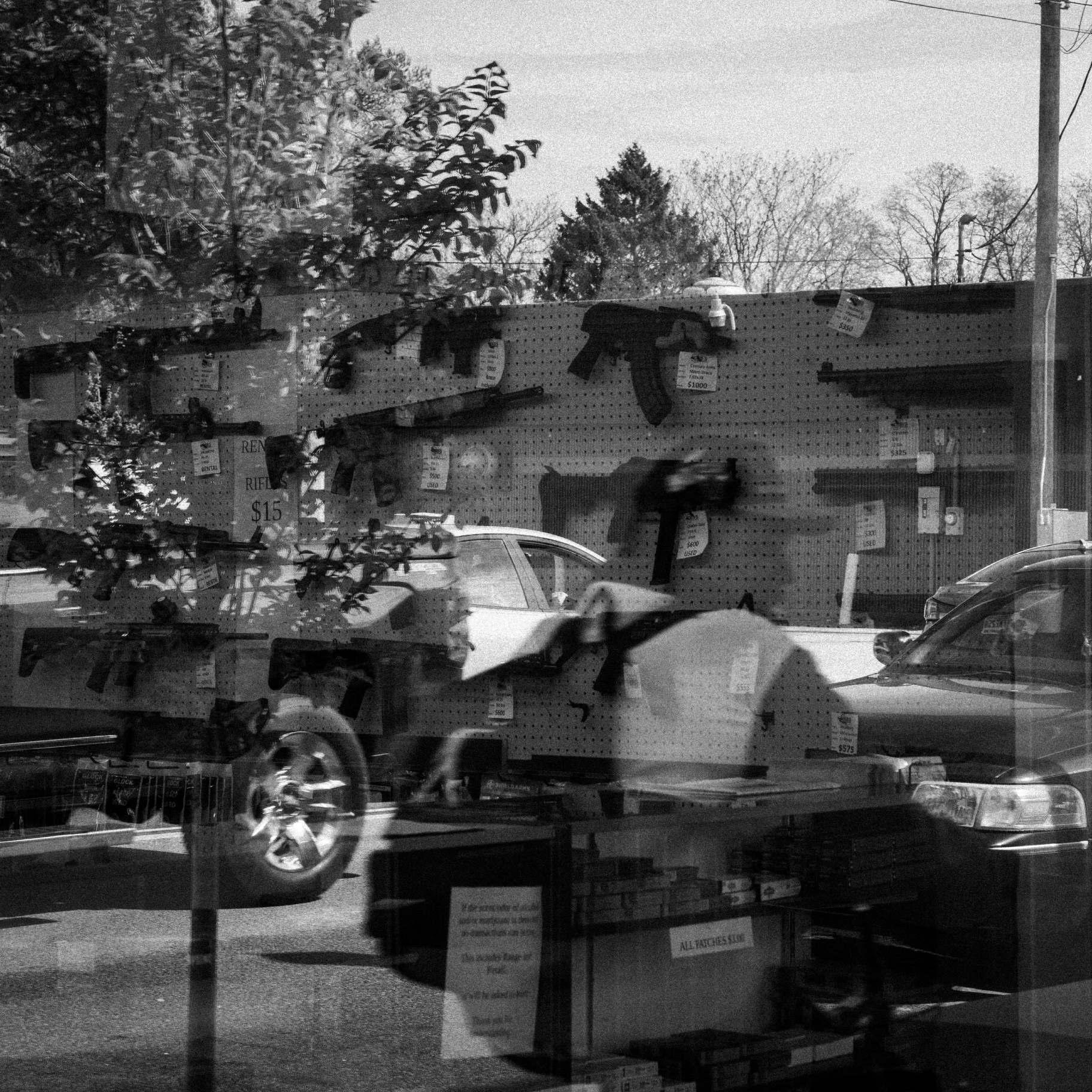 A man glances inside Deb’s Gun Range while passing by on a bicycle. (Sarahbeth Maney / ProPublica)