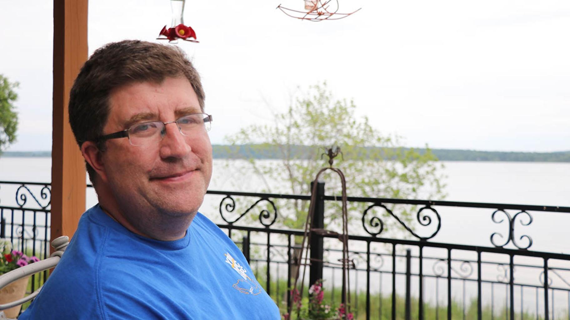 Luke Harvey, owner of the Riverview Road Apiary, sits on the back porch of his family home in Chillicothe along the Illinois River. (Tom O’Connor / Medill Illinois News Bureau)