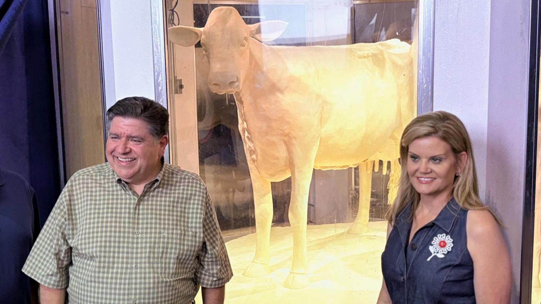 Gov. JB Pritzker and wife MK pose for a photo with the 2025 butter cow. (Jerry Nowicki / Capitol News Illinois)