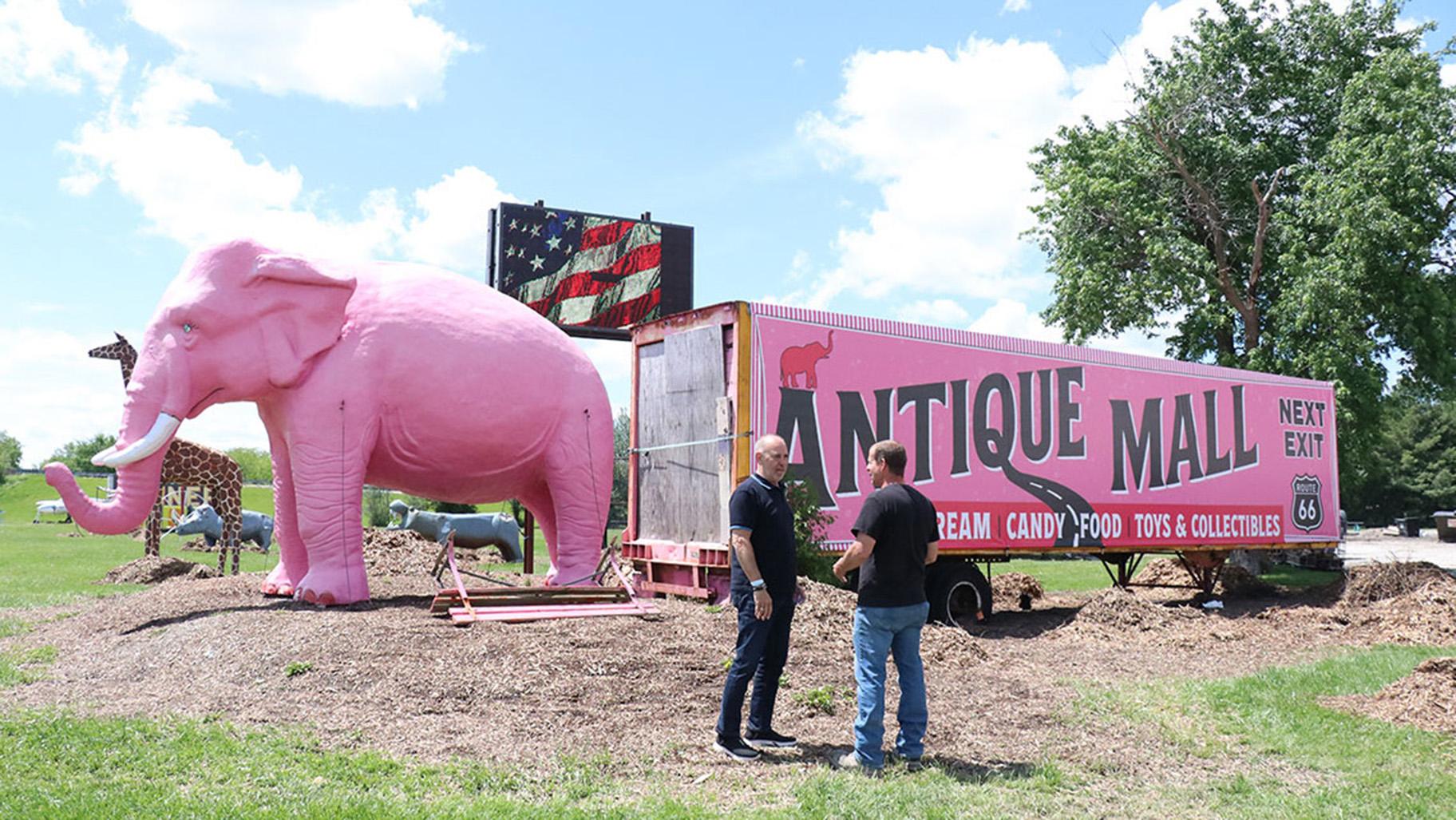 Felipe de la Cruz Tenorio and Wayne Pickerill stood in front of the iconic pink elephant statue and vintage trailer at the Pink Elephant Antique Mall. (Chloe Park / Medill Illinois News Bureau)
