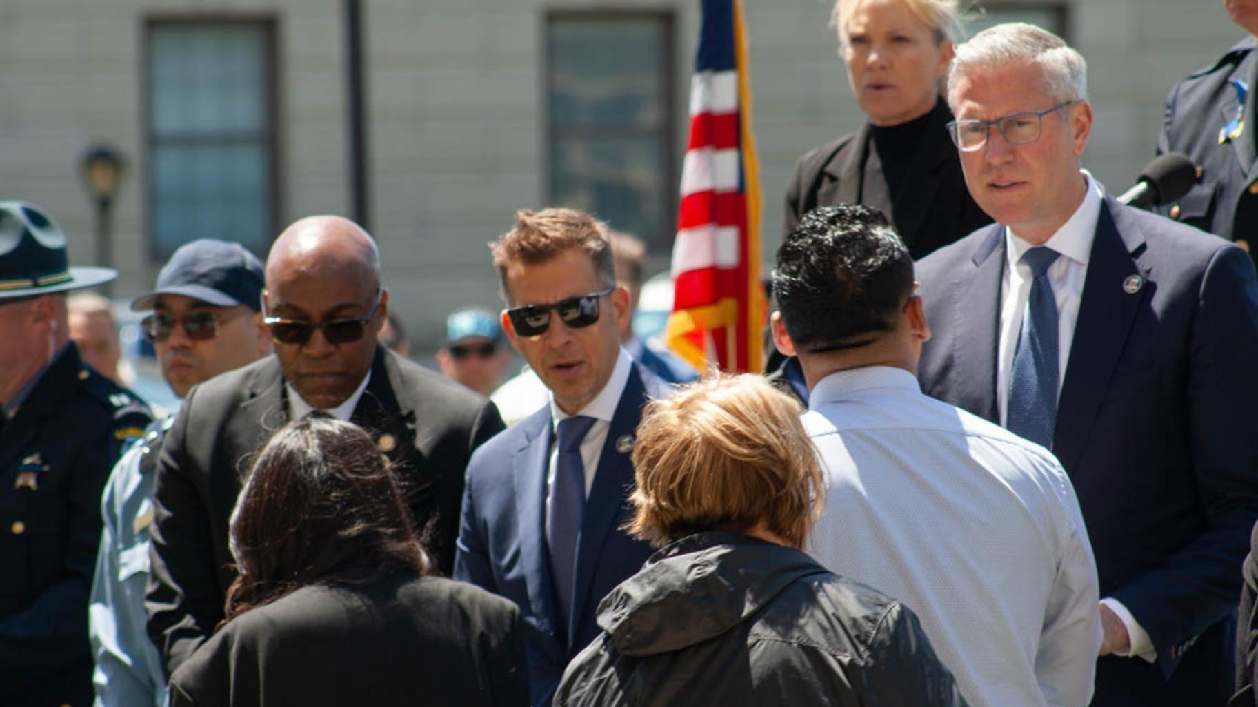 Attorney General Kwame Raoul, Secretary of State Alexi Giannoulias and state Treasurer Michael Frerichs speak with the family members of Krystal Rivera, who was killed in the line of duty in June 2025. She was one of two officers honored in an annual ceremony on May 7, 2026. (Jenna Schweikert / Capitol News Illinois)