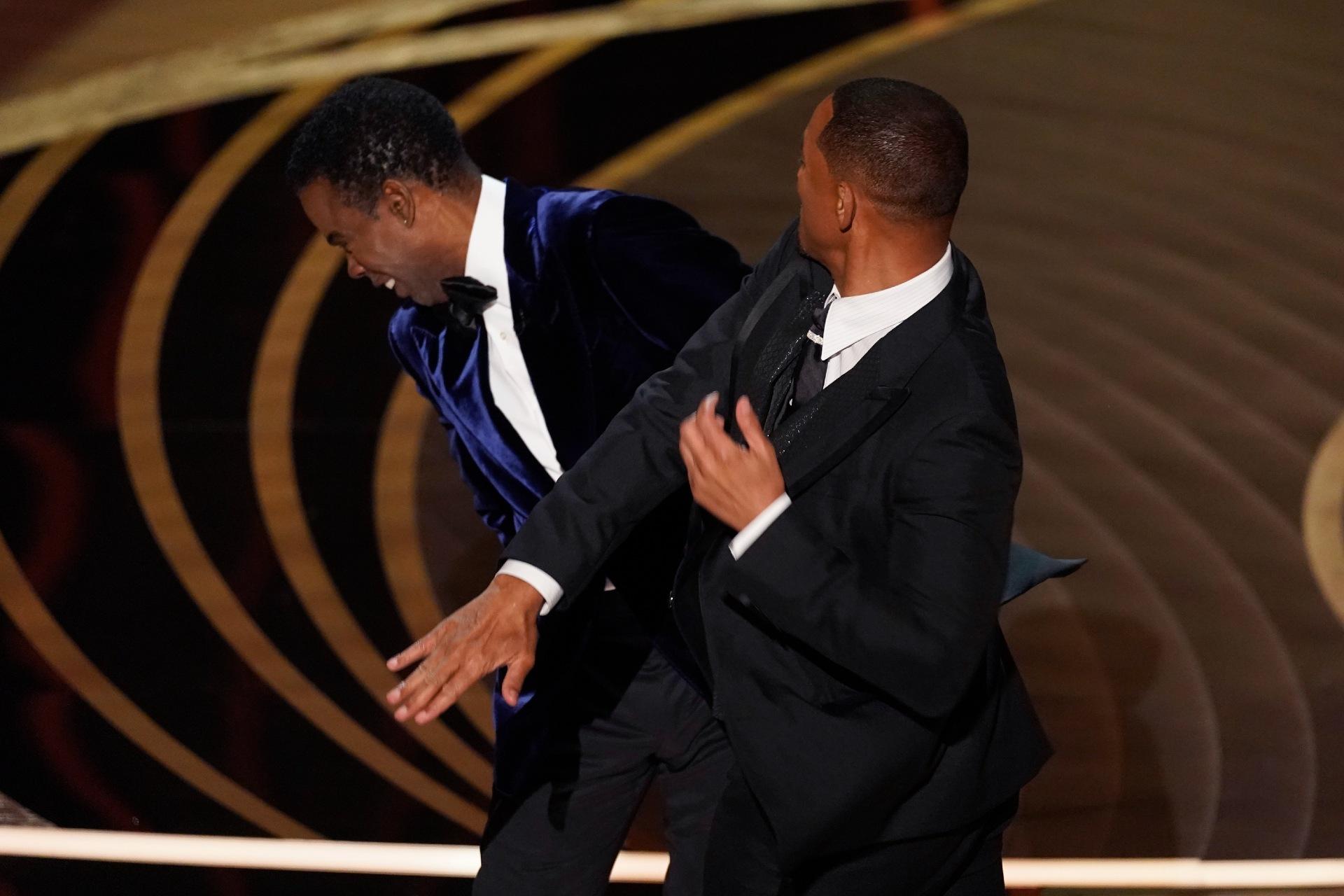 Will Smith, right, hits presenter Chris Rock on stage while presenting the award for best documentary feature at the Oscars on Sunday, March 27, 2022, at the Dolby Theatre in Los Angeles. (AP Photo / Chris Pizzello)