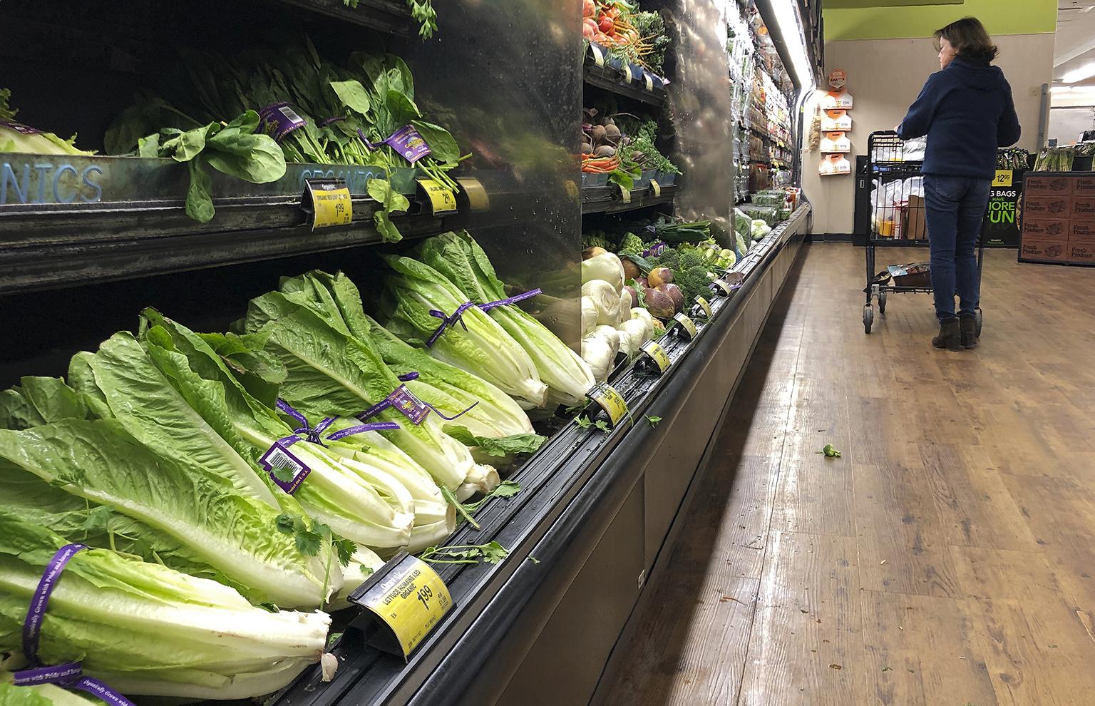 Romaine lettuce still sits on the shelves as a shopper walks through the produce area of an Albertsons market Tuesday, Nov. 20, 2018, in Simi Valley, Calif. Health officials in the U.S. and Canada told people Tuesday to stop eating romaine lettuce because of a new E. coli outbreak. (Mark J. Terrill / AP Photo)