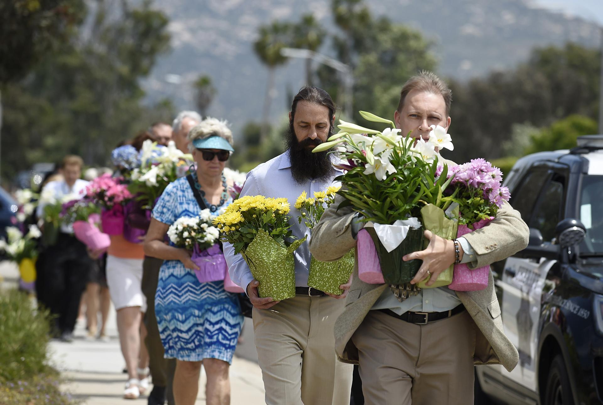 Members of the St. John of Damascus Orthodox Church bring flowers to a memorial at the Chabad of Poway synagogue, Sunday, April 28, 2019, in Poway, California. (AP Photo / Denis Poroy)