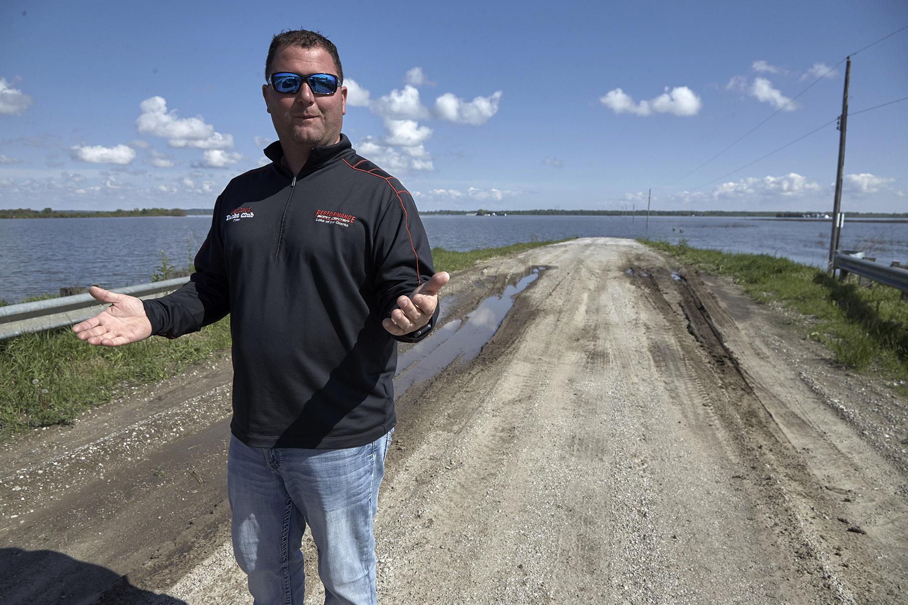 In this May 10, 2019 photo, Brett Adams gestures as he stands where the road to his flooded farm disappears under flood waters, with the farm buildings seen in the background, in Peru, Neb. (AP Photo / Nati Harnik)