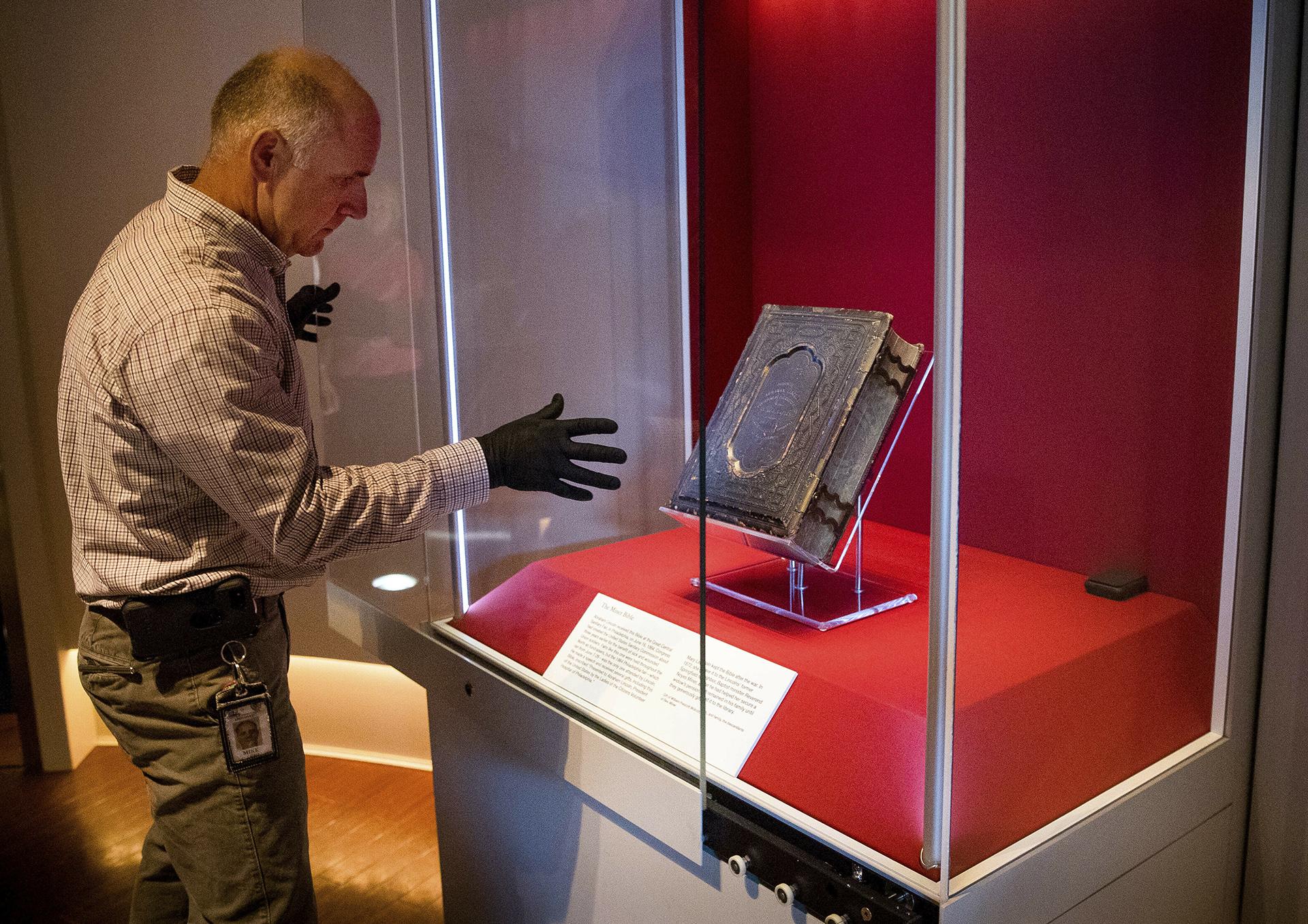 Mike Casey, exhibits project manager at the Abraham Lincoln Presidential Museum, moves the newly acquired Bible that belonged to Abraham Lincoln in his final year of life, into an exhibit at the museum following a press conference announcing its arrival Thursday, June 20, 2019, in Springfield, Illinois. (Ted Schurter / The State Journal-Register via AP)