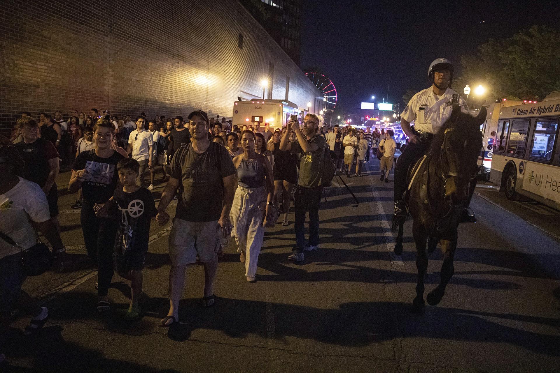 In this Thursday, July 4, 2019 photo, A Chicago Police Department officer guards people as they stream out of Chicago’s Navy Pier after reports of stabbings and threatening injuries after the 4th of July celebrations. (AP Photo / Amr Alfiky)