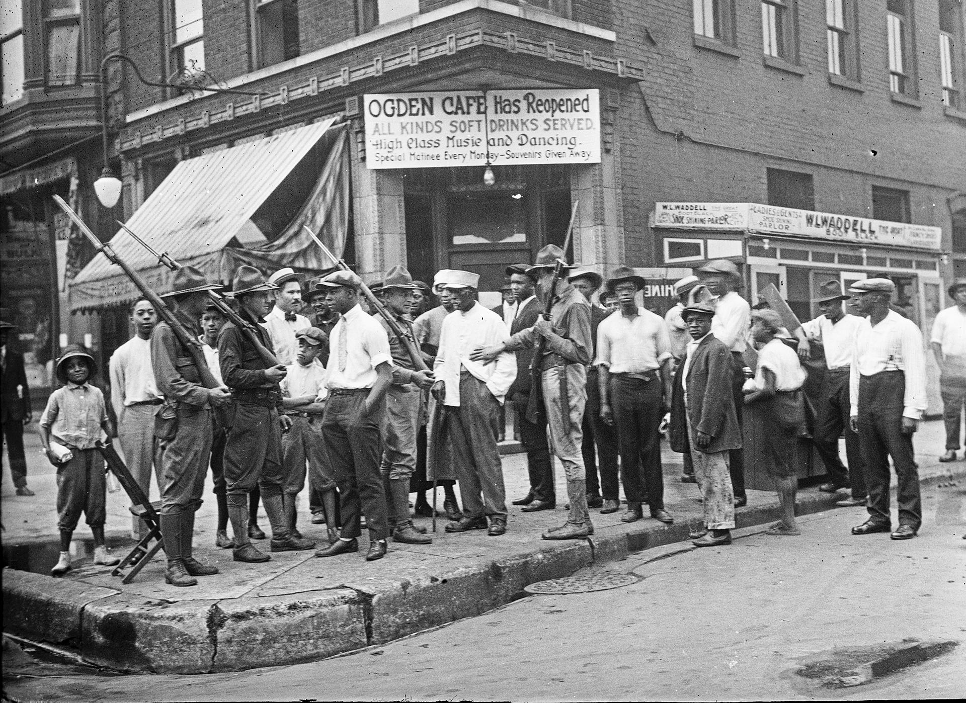 In this 1919 photo provided by Chicago History Museum, a crowd of men and armed National Guard stand in front of the Ogden Cafe during race riots in Chicago. (Chicago History Museum / The Jun Fujita negatives collection via AP)