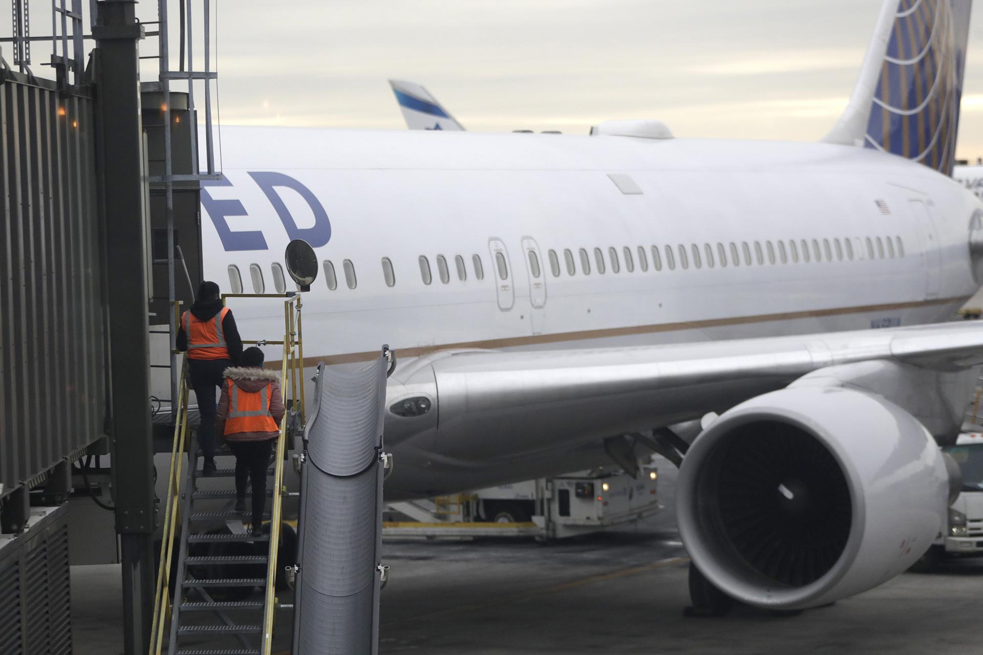 In this Jan. 23, 2019, photo employees walk up a ramp toward a ramp where a United Airlines jet is parked at a gate Newark Liberty International Airport in Newark, New Jersey. (AP Photo / Julio Cortez)