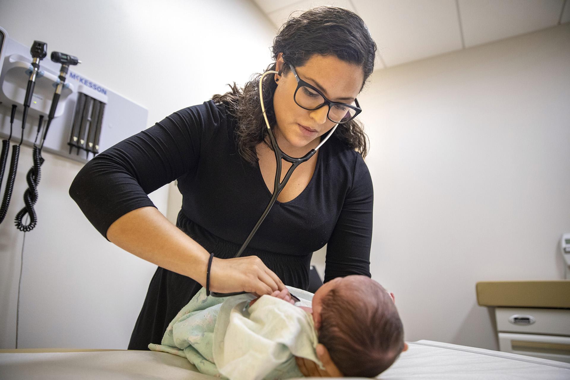 In this Tuesday, Aug. 13, 2019, photo, Dr. Jasmine Saavedra, a pediatrician at Esperanza Health Centers whose parents emigrated from Mexico in the 1980s, examines Alondra Marquez, a newborn baby in her clinic in Chicago. (AP Photo / Amr Alfiky)