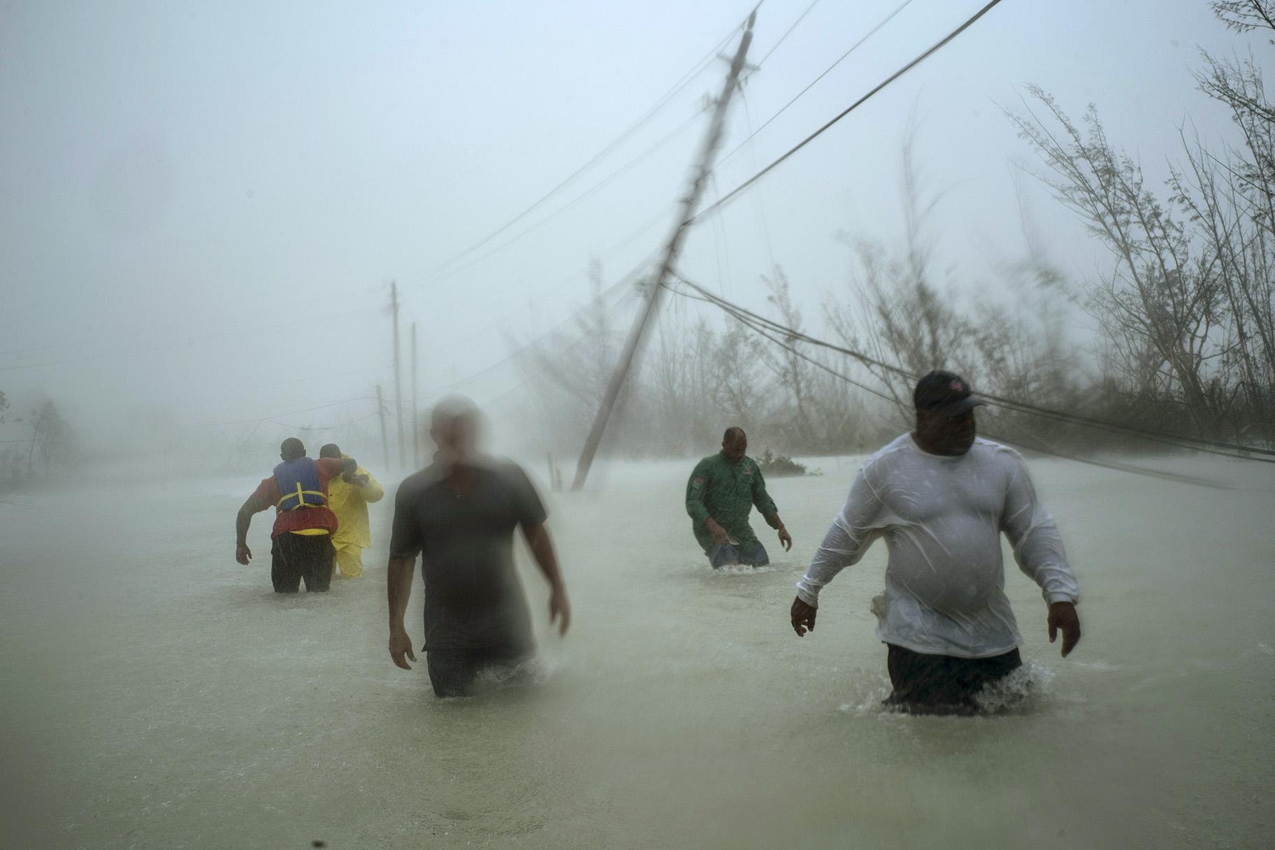 Volunteers walk under the wind and rain from Hurricane Dorian through a flooded road as they work to rescue families near the Causarina bridge in Freeport, Grand Bahama, Bahamas on Tuesday, Sept. 3, 2019. The storm’s punishing winds and muddy brown floodwaters devastated thousands of homes, crippled hospitals and trapped people in attics. (AP Photo / Ramon Espinosa)