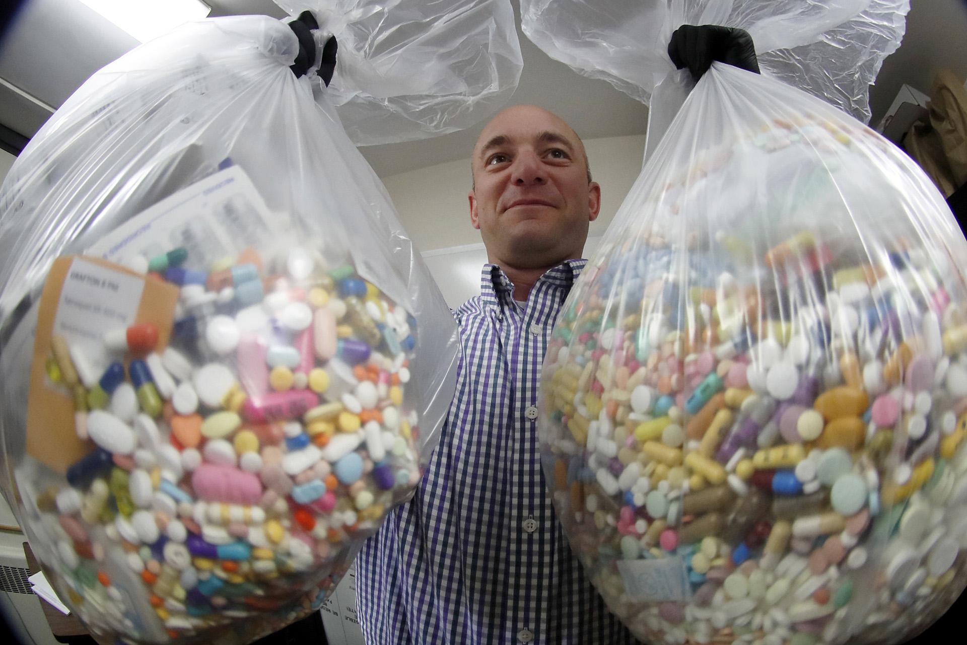 Narcotics detective Ben Hill, with the Barberton Police Department, shows two bags of medications that are stored in their headquarters and slated for destruction, Wednesday, Sept. 11, 2019, in Barberton, Ohio. (AP Photo / Keith Srakocic)