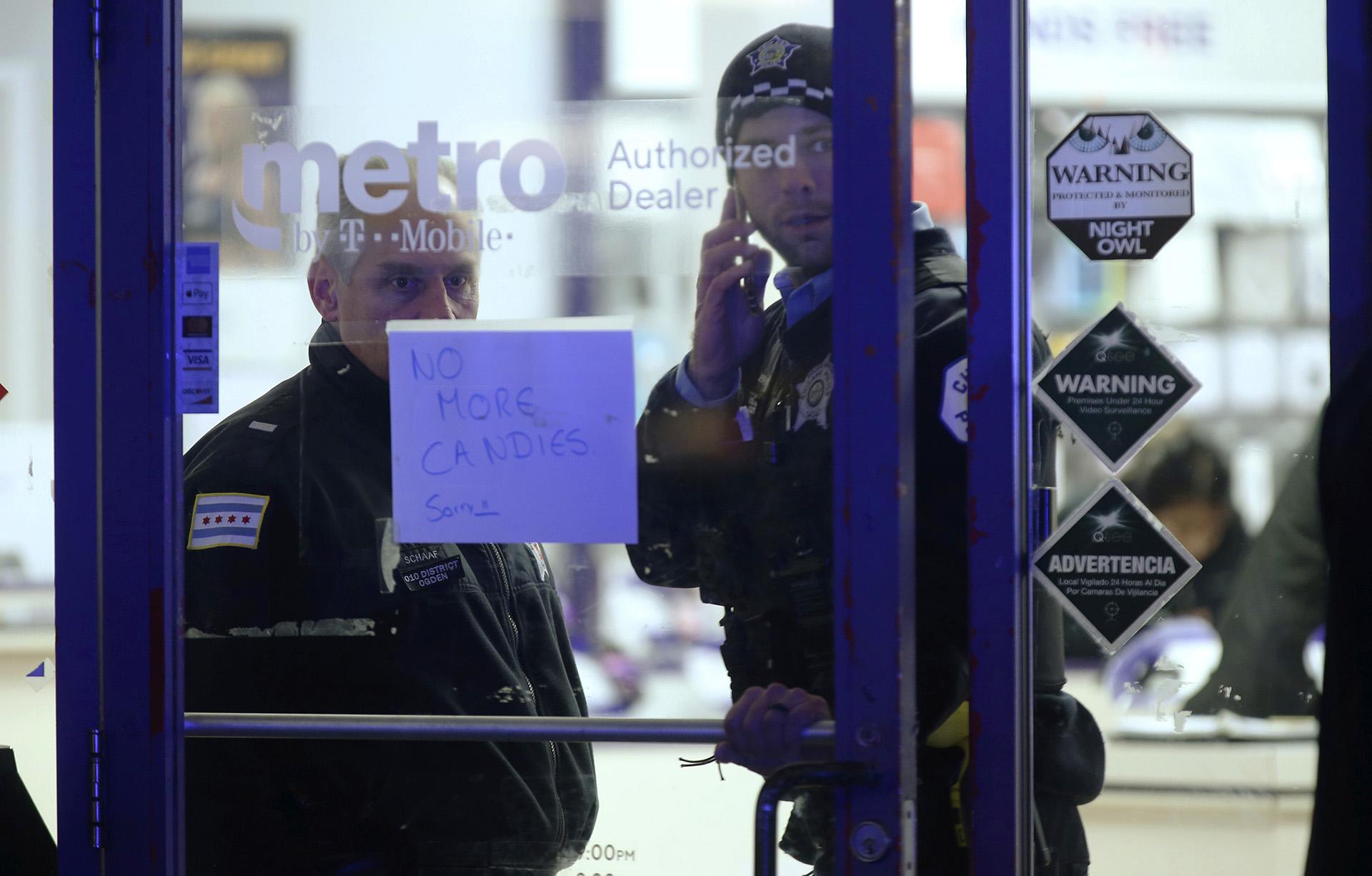 A police supervisor and officer stand inside a cell phone store in the 3700 block of West 26th Street, where a 7-year-old girl was shot while trick-or-treating Thursday, Oct. 31, 2019, in Chicago. (John J. Kim / Chicago Tribune via AP)