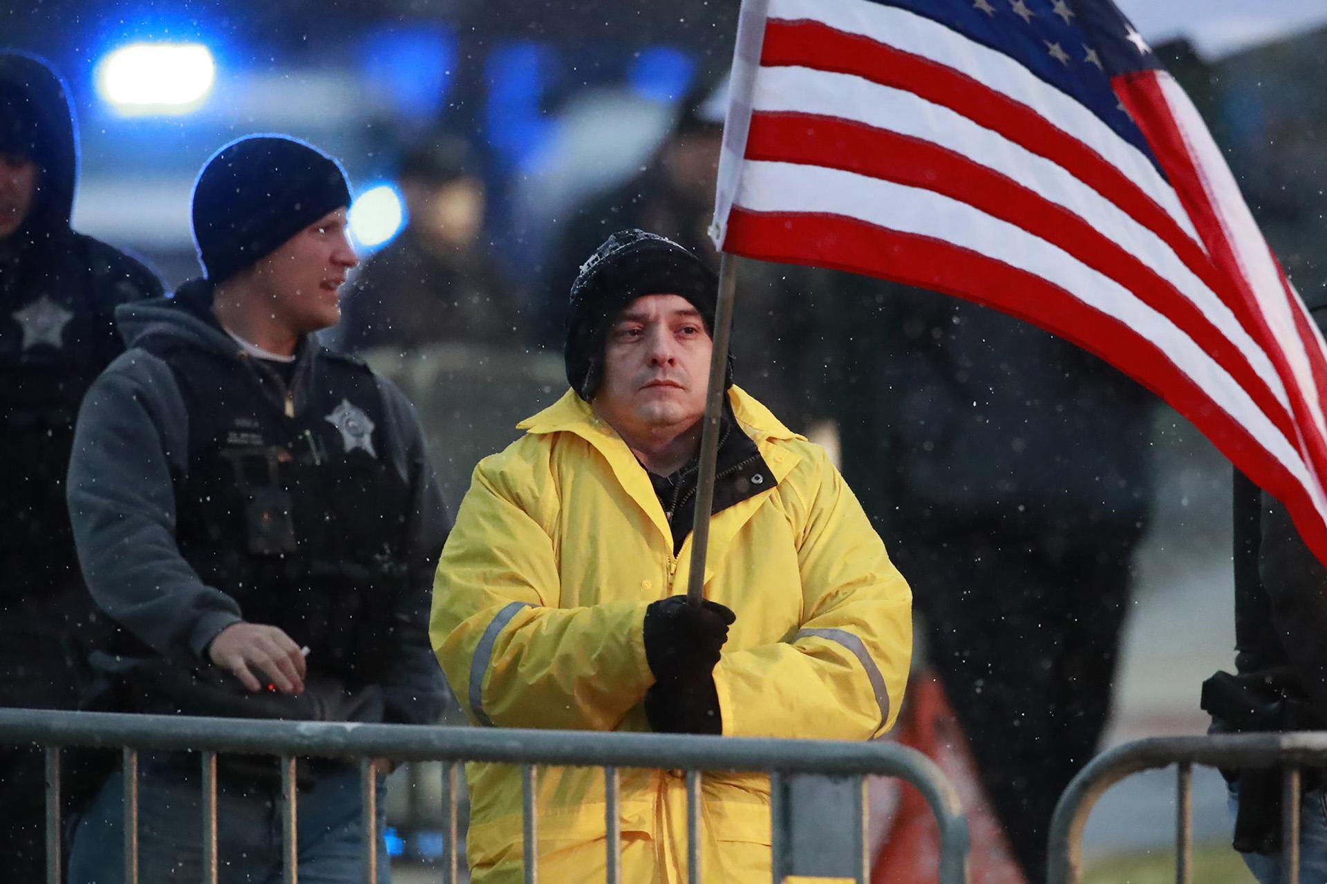 In this Nov. 25, 2018 file photo, State Rep. Jaime Andrade holds a flag outside the visitation for Chicago police Officer Samuel Jimenez at a funeral home in Des Plaines, Illinois. Andrade said he registered as a Chicago lobbyist and started charging for his services when the state budget crisis from 2015 to 2017 forced lawmakers to go without paychecks. (Nuccio DiNuzzo / Chicago Tribune via AP File)