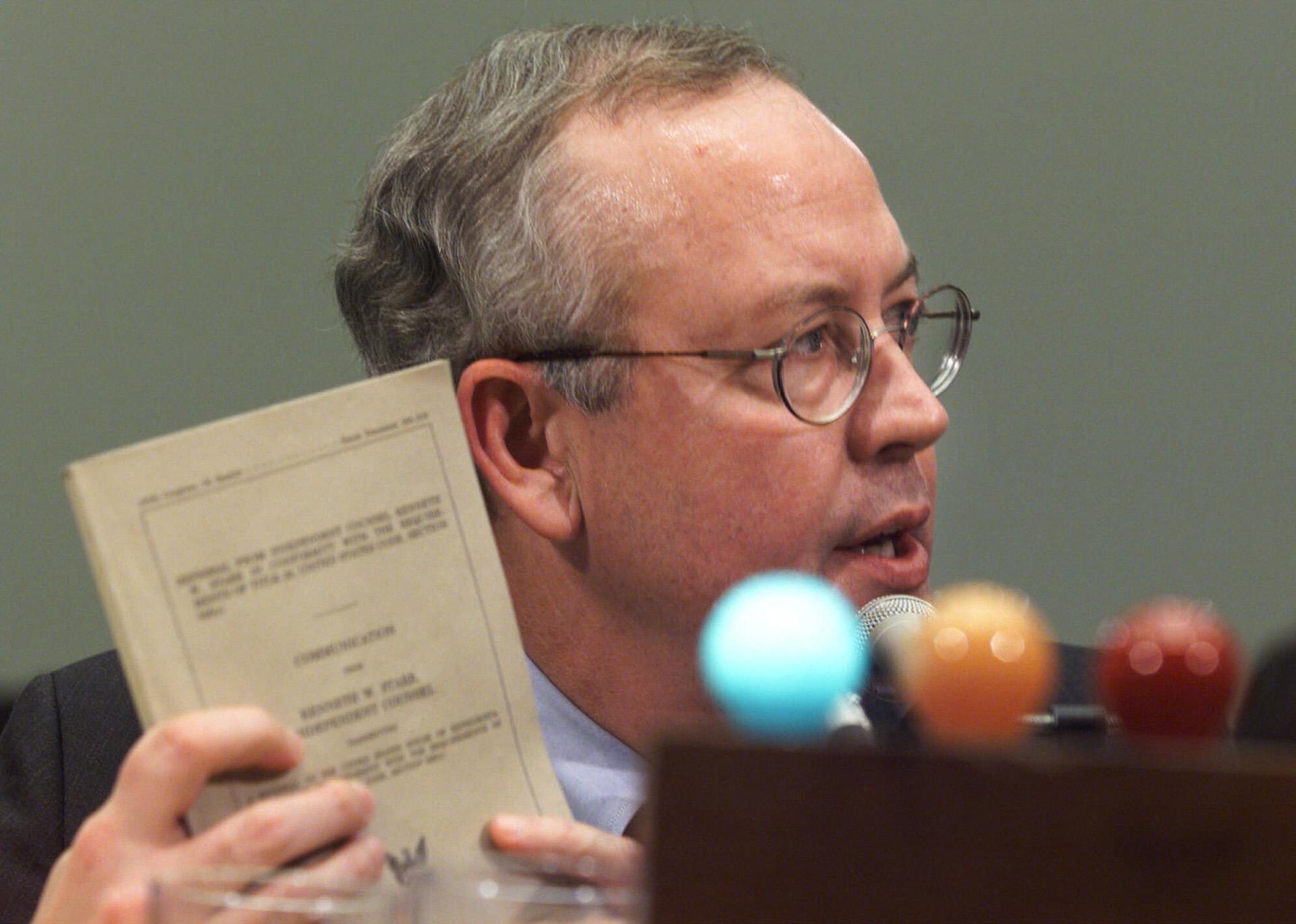 In this Nov. 19, 1998 file photo, Independent Counsel Kenneth Starr holds up his report while testifying on Capitol Hill, before the House Judiciary Committee’s impeachment hearing. (AP Photo / Joe Marquette)